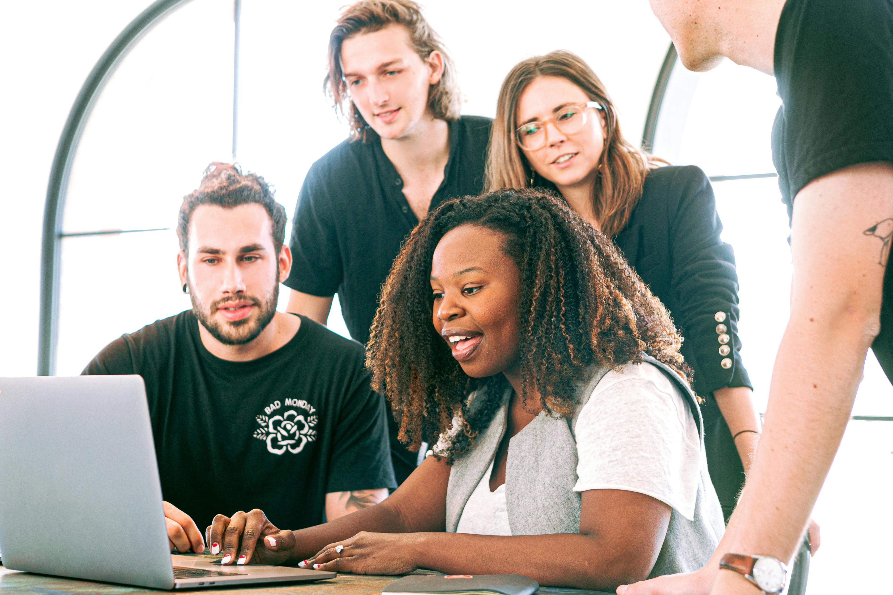 A group of people looking at a laptop together
