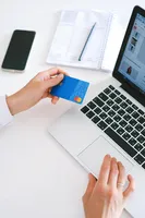 A person looking at their credit card while using their laptop
